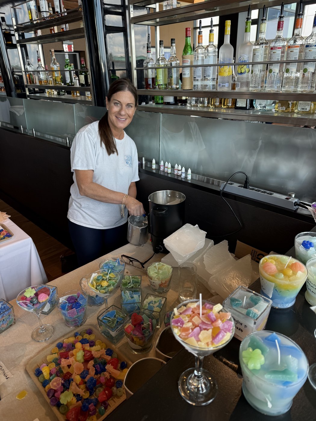 A smiling guest with colorful wax and handmade candles at a group candle-making event