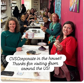 Corporate guests smiling together with painted pottery at a studio table