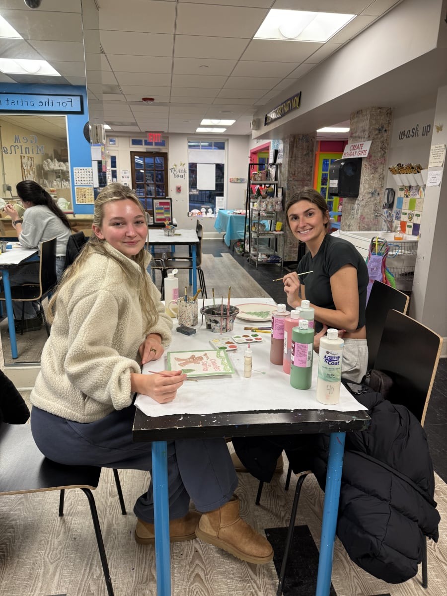 Two adults smiling while painting pottery together at The Painting Place